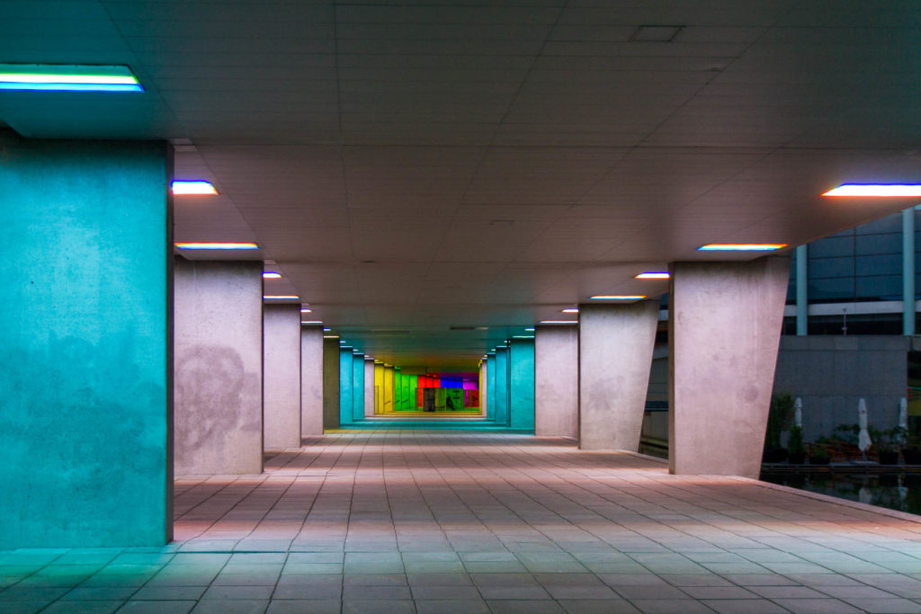 un tunnel en béton aux murs colorés par des lumières différentes