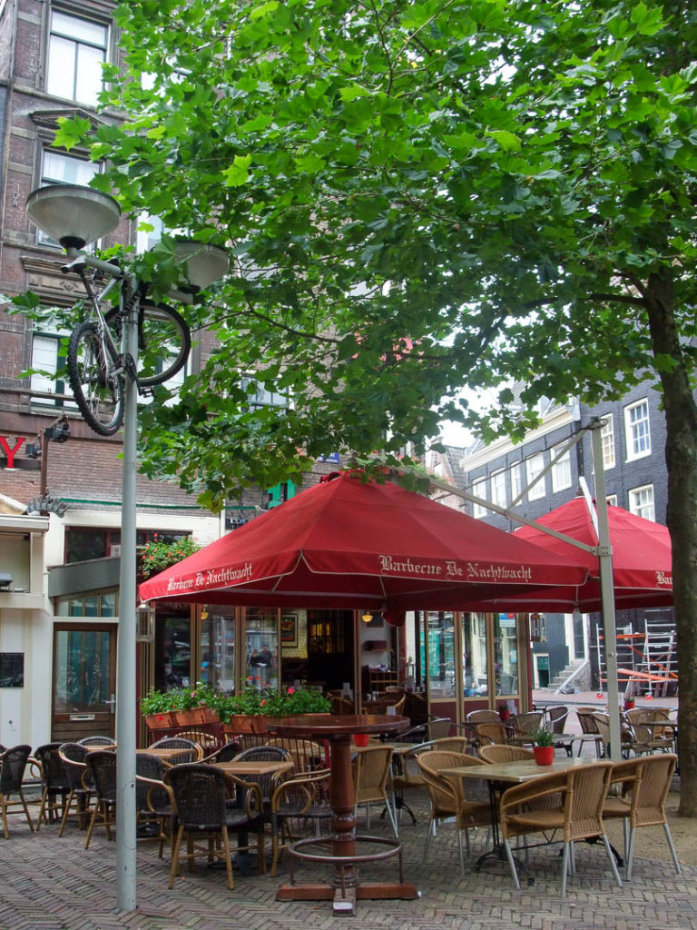 terrasse d'un bistrot avec un vélo accroché en haut d'un lampadaire