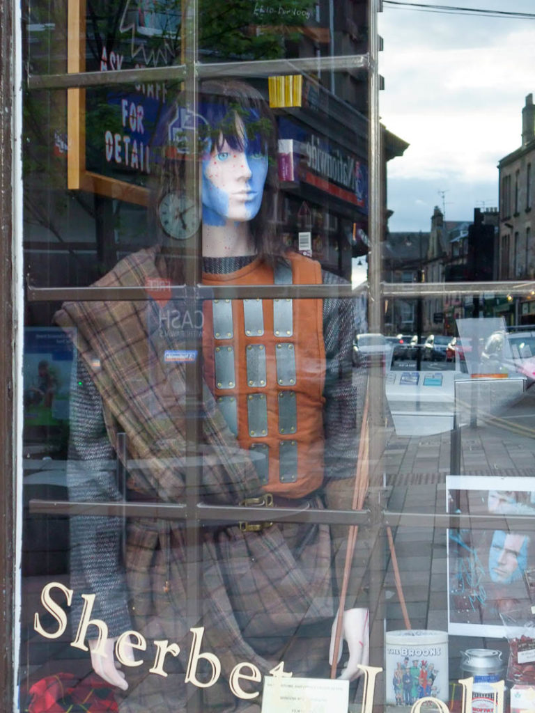 mannequin Highlander dans une vitrine qui reflète la ville de Stirling