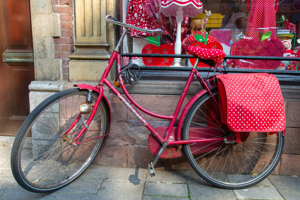 un vélo rouge à pois blancs garé sur une vitrine qui vend des objets rouges à pois blancs
