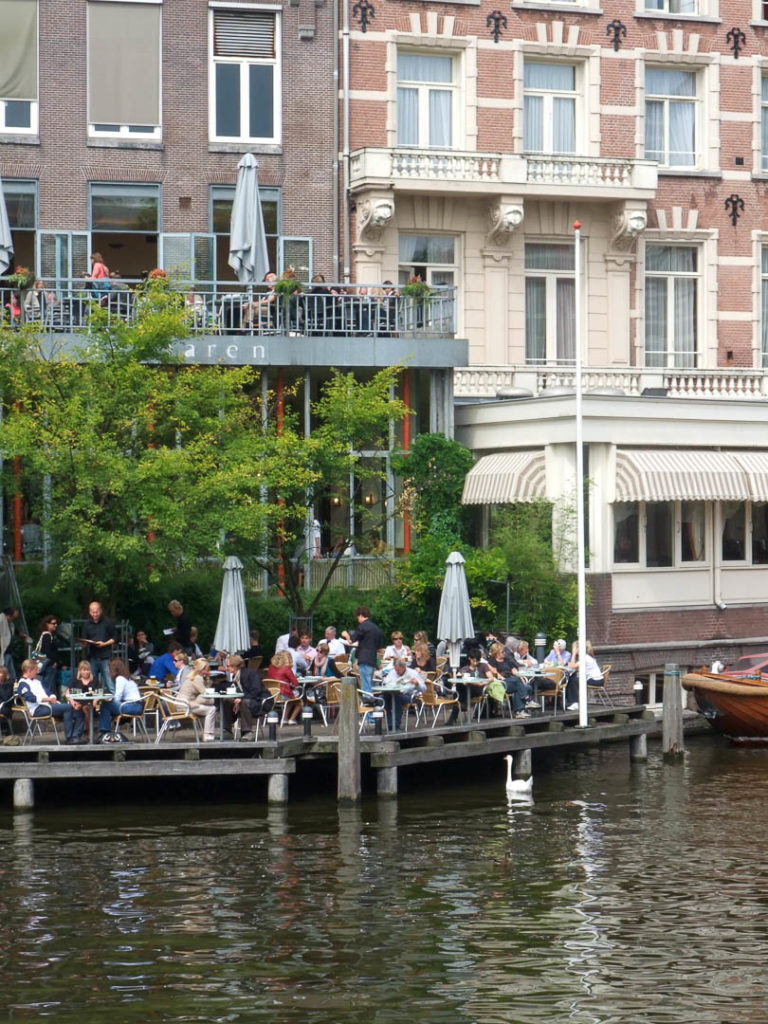 des gens profitent d'une terrasse au-dessus d'un canal